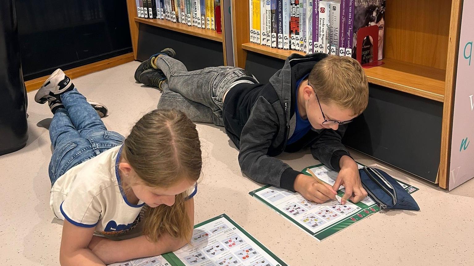 Twee kinderen van Christelijke basisschool De Ark in Daarle zijn bezig met een lesactiviteit op de vloer van de schoolbibliotheek. Twee kinderen van Christelijke basisschool De Ark in Daarle zijn bezig met een lesactiviteit op de vloer van de schoolbibliotheek.