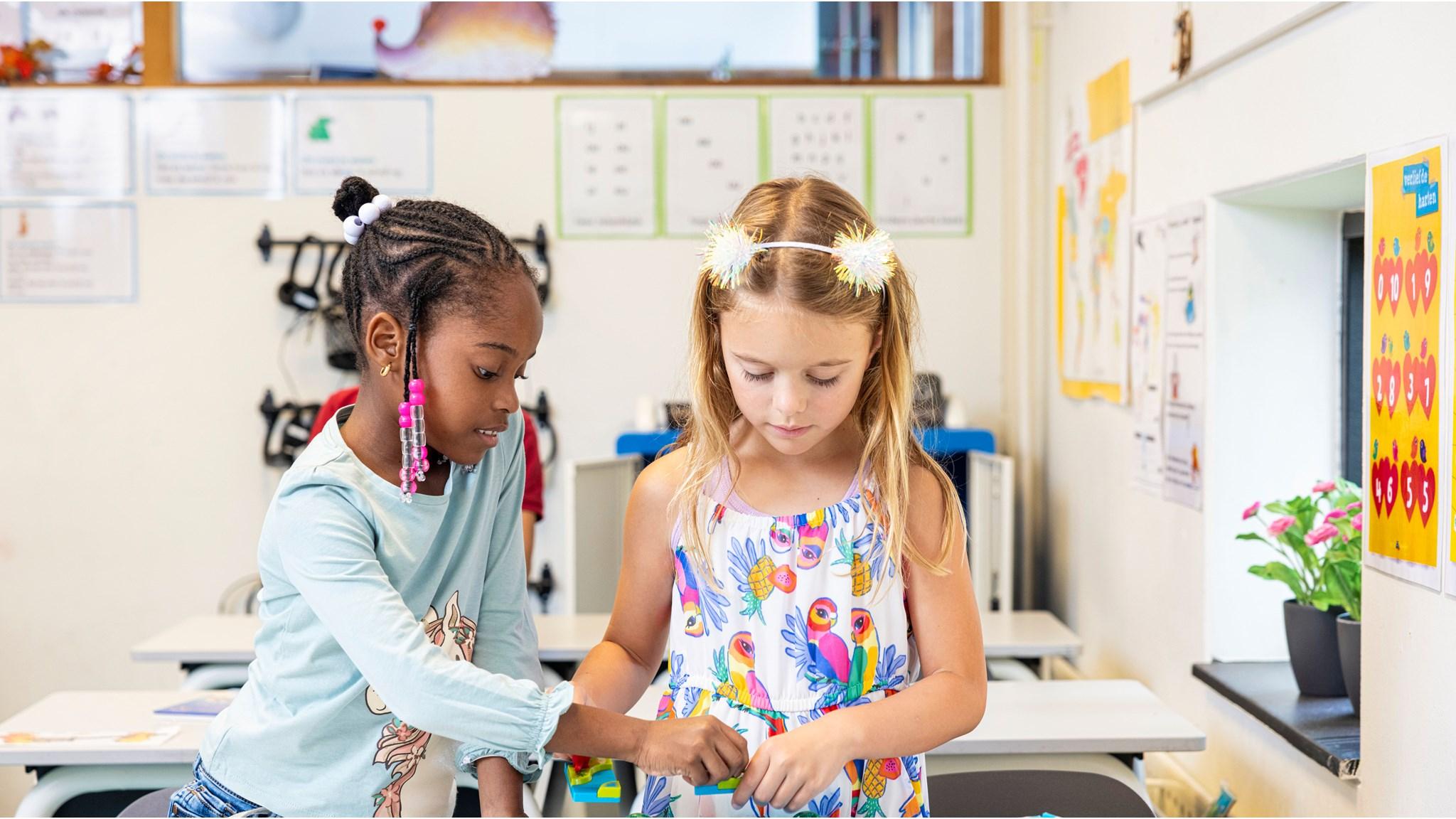 Twee kinderen werken samen aan een opdracht in de klas van Openbare Basisschool De Zevensprong in Almere. Twee kinderen werken samen aan een opdracht in de klas van Openbare Basisschool De Zevensprong in Almere.