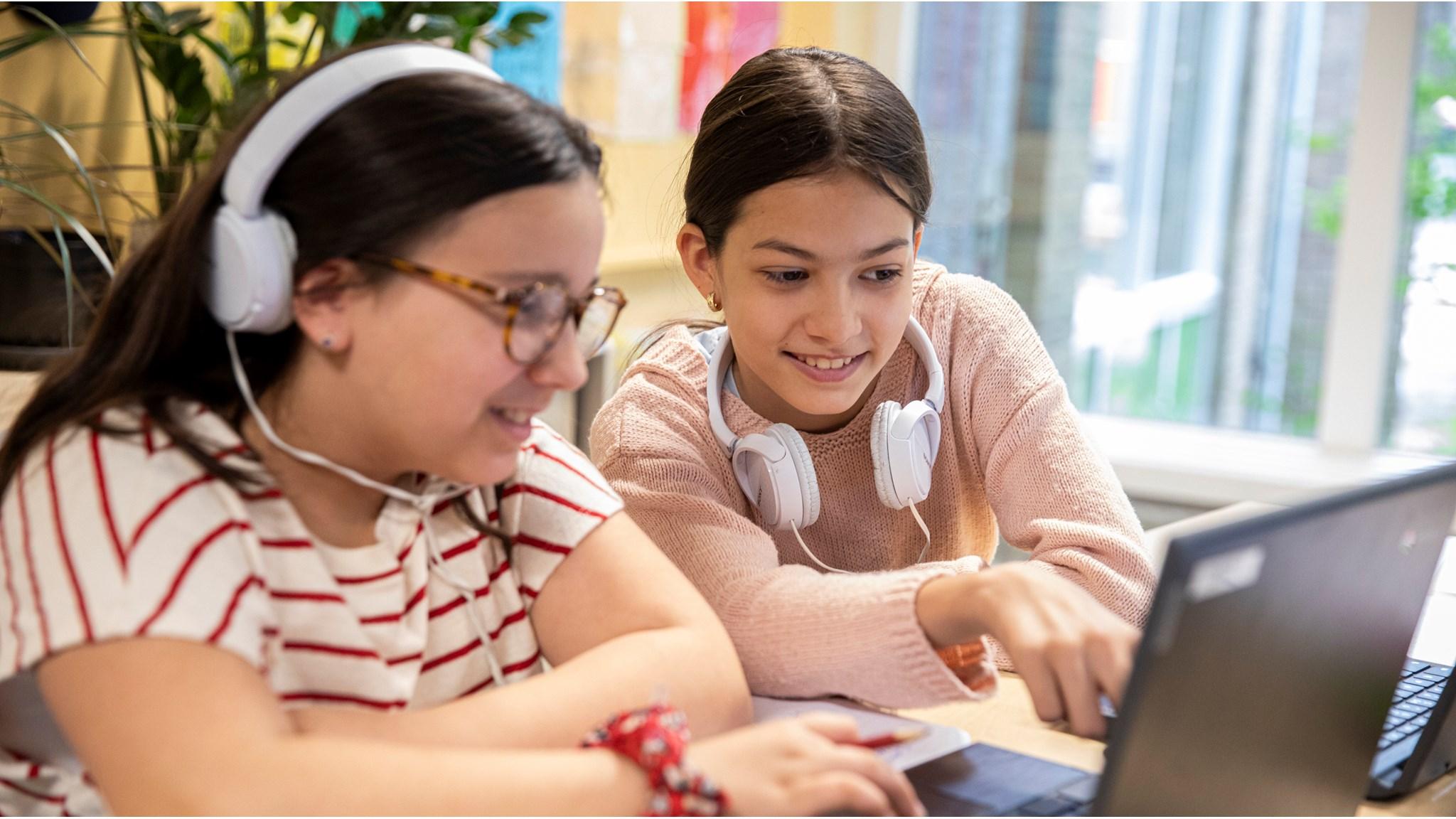 Twee kinderen werken samen op een laptop met koptelefoons op OBS Maaspleinschool in Utrecht. Twee kinderen werken samen op een laptop met koptelefoons op OBS Maaspleinschool in Utrecht.