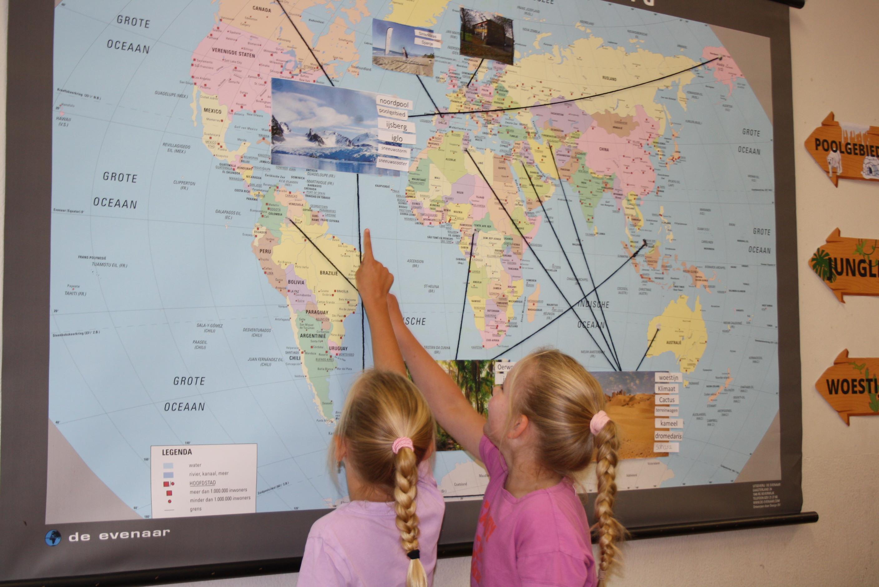 Twee kinderen wijzen naar een wereldkaart in Basisschool Jan Ligthart in Zelhem.