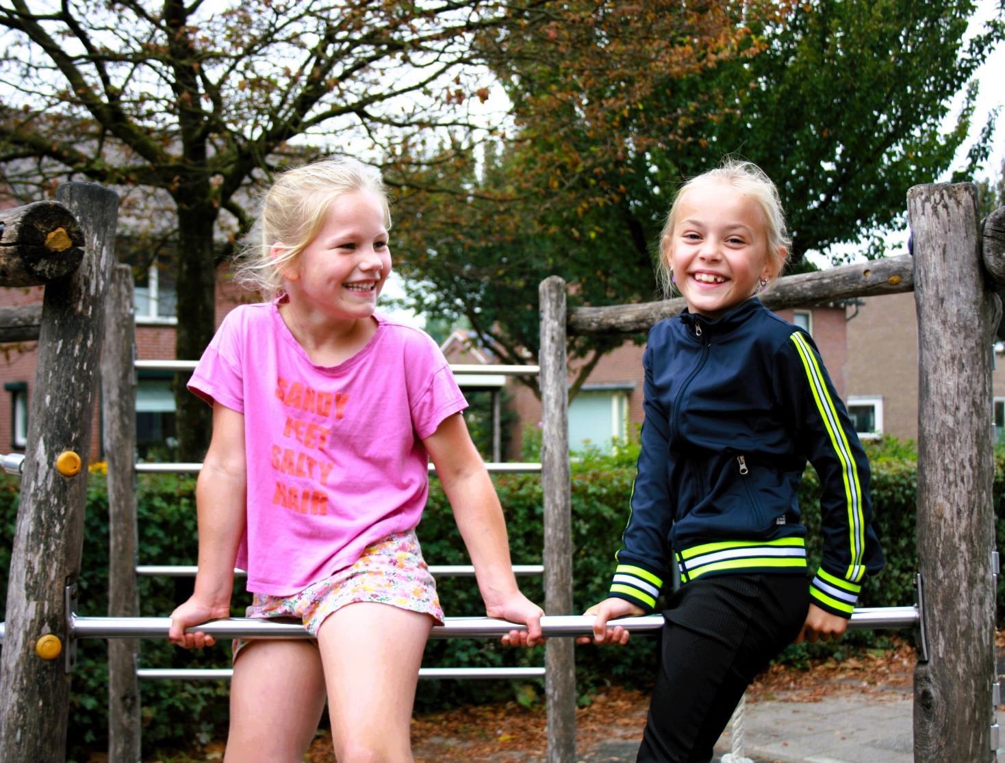 Twee lachende meisjes spelen op het schoolplein van Basisschool Jan Ligthart in Zelhem.