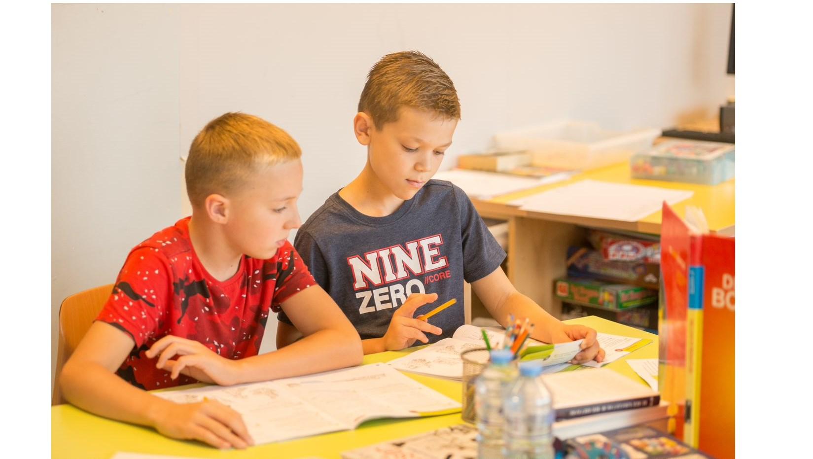 Twee leerlingen aan de Mgr. Bekkersschool in Spijkenisse leren samen aan een kleurrijke tafel.