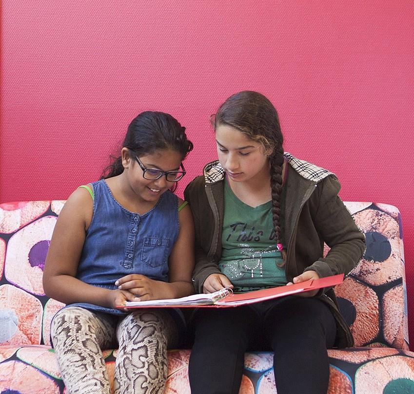 Twee leerlingen bekijken samen hun schoolwerk op een bank in De Kwartiermaker in Den Bosch. Twee leerlingen bekijken samen hun schoolwerk op een bank in De Kwartiermaker in Den Bosch.