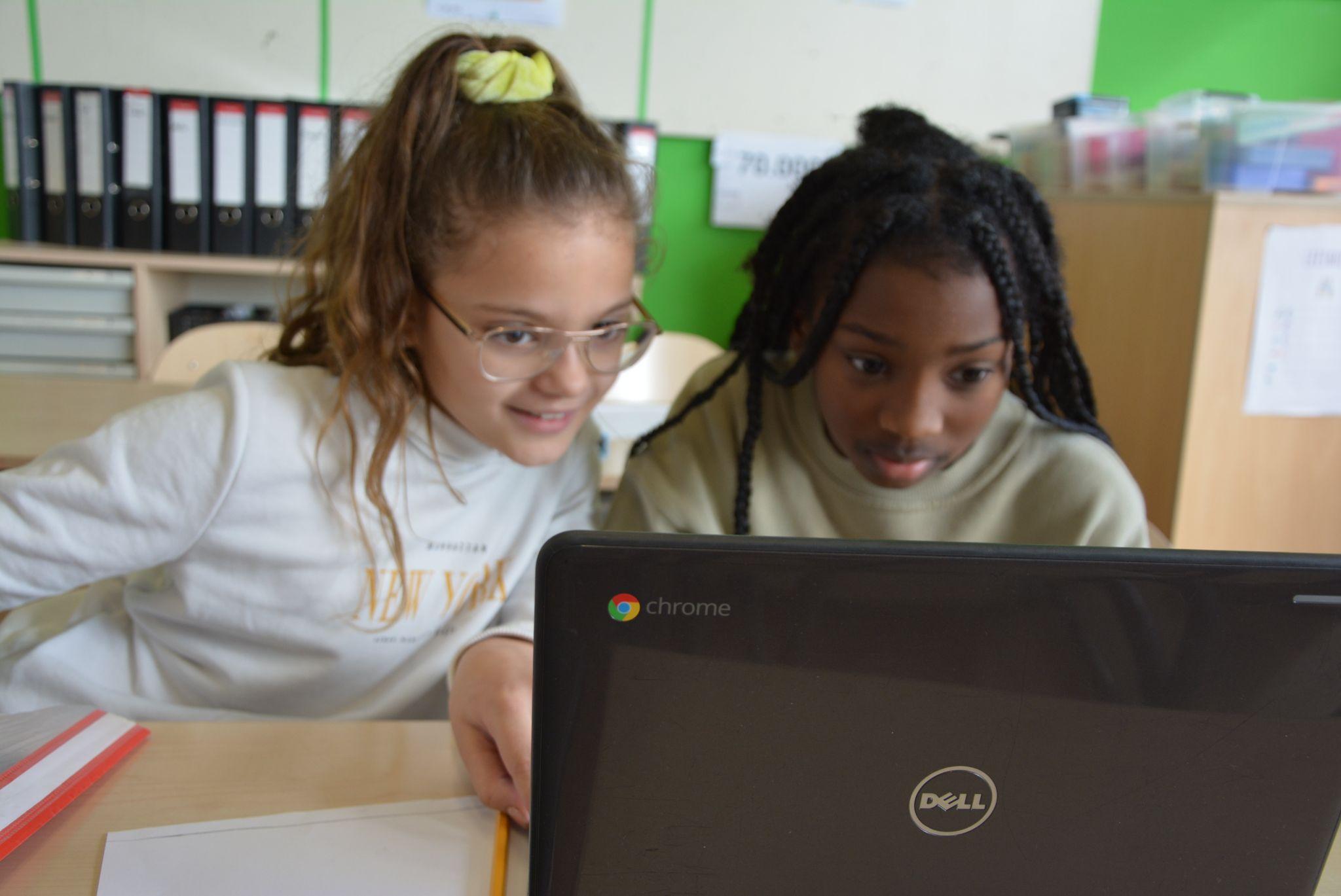 Twee leerlingen van CBS De Klimop in Ridderkerk kijken samen naar een laptop. Twee leerlingen van CBS De Klimop in Ridderkerk kijken samen naar een laptop.