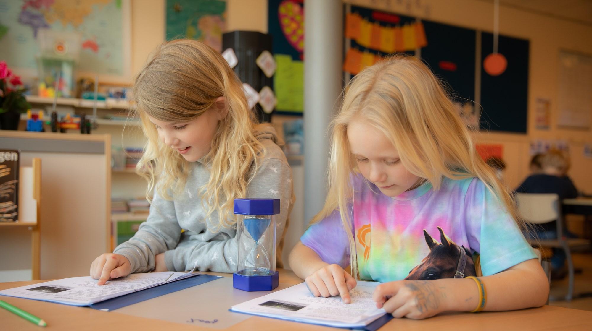 Twee leerlingen van De Gooise Daltonschool in Hilversum zijn gefocust op hun studie met boeken en een zandloper op tafel. Twee leerlingen van De Gooise Daltonschool in Hilversum zijn gefocust op hun studie met boeken en een zandloper op tafel.