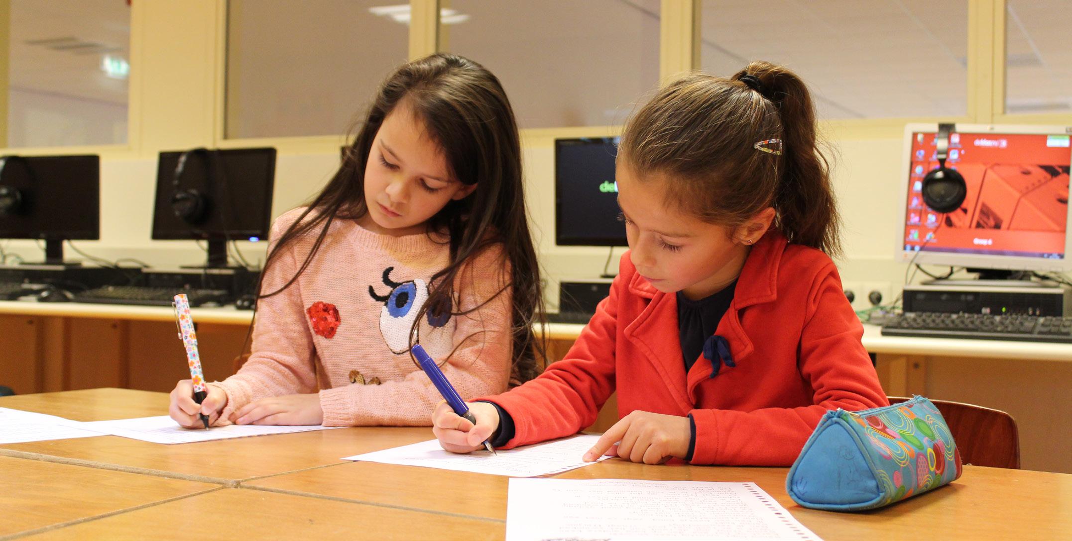 Twee leerlingen van de Paasbergschool in Ede zijn aan het schrijven tijdens een les.
