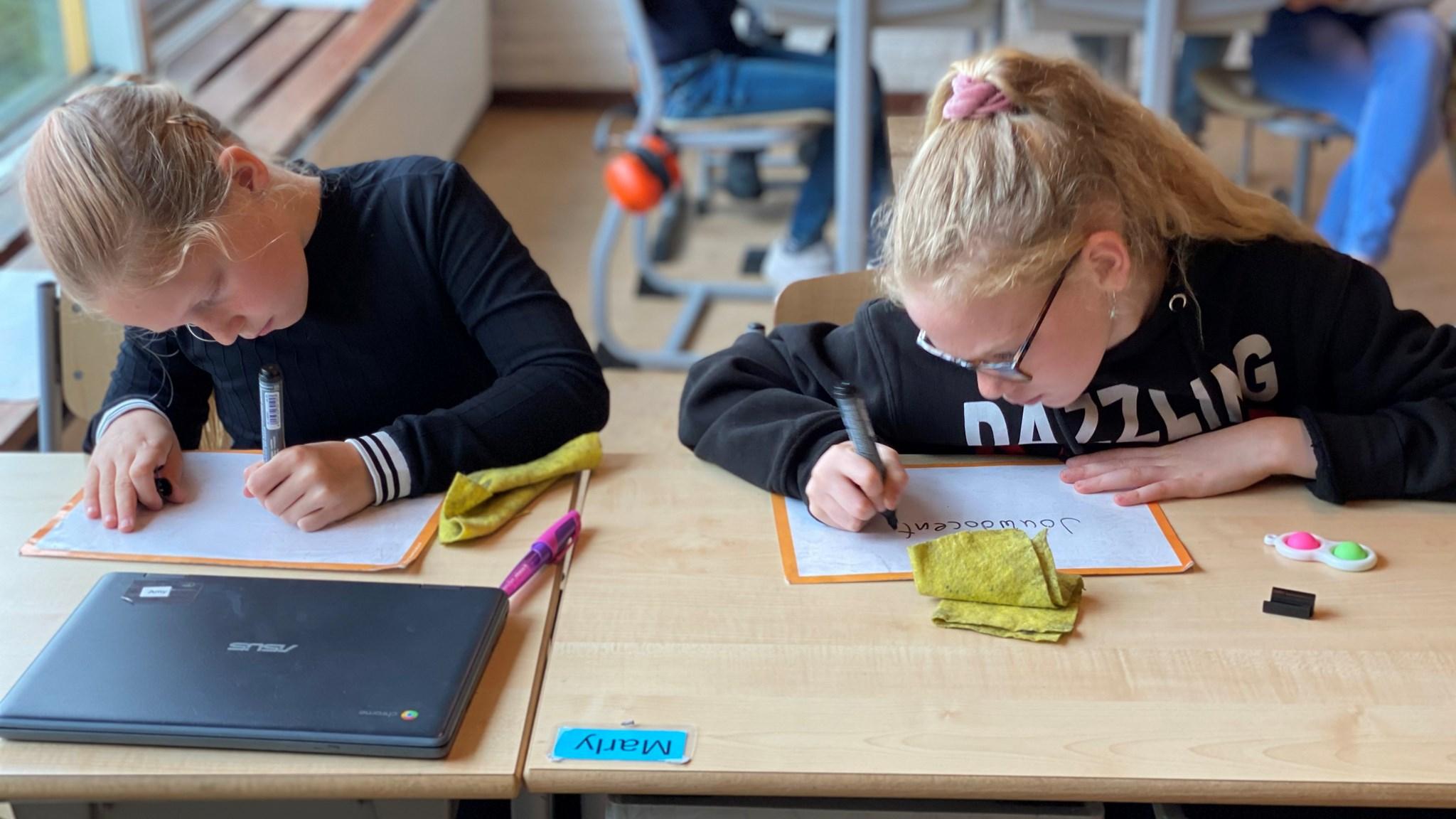 Twee leerlingen van Kindcentrum De Bussel in Blokker zijn bezig met schrijven aan hun bureau. Twee leerlingen van Kindcentrum De Bussel in Blokker zijn bezig met schrijven aan hun bureau.