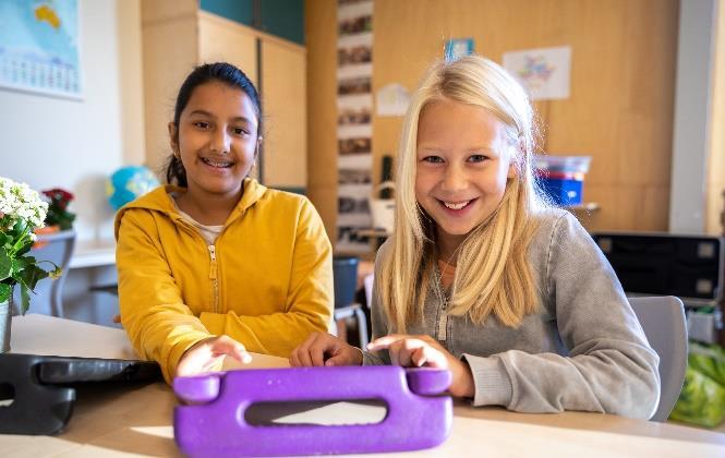 Twee leerlingen van Sterrenschool Hilversum genieten van een activiteit met een tablet in de klas. Twee leerlingen van Sterrenschool Hilversum genieten van een activiteit met een tablet in de klas.