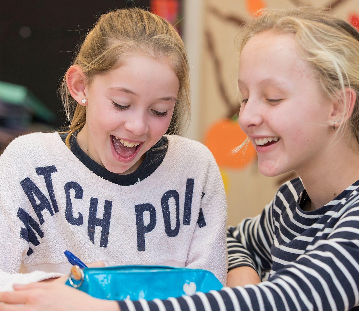 Twee meisjes beginnen enthousiast te lachen en te praten terwijl ze samen aan het werk zijn op de Houtrustschool in Den Haag. Twee meisjes beginnen enthousiast te lachen en te praten terwijl ze samen aan het werk zijn op de Houtrustschool in Den Haag.