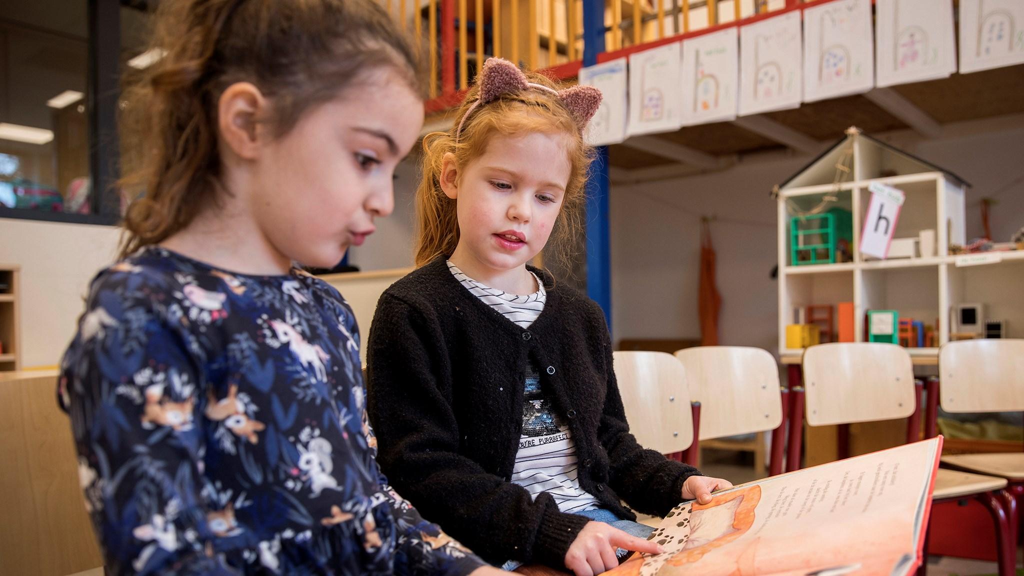 Twee meisjes lezen samen een boek in De Wilakkers in Eindhoven. Twee meisjes lezen samen een boek in De Wilakkers in Eindhoven.