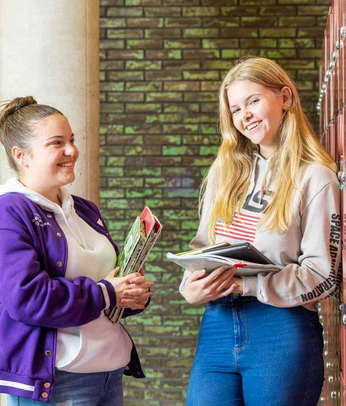 Twee studenten met schoolboeken lachen naar elkaar in de gang van Montessori Campus 0-18 PO in Almere. Twee studenten met schoolboeken lachen naar elkaar in de gang van Montessori Campus 0-18 PO in Almere.