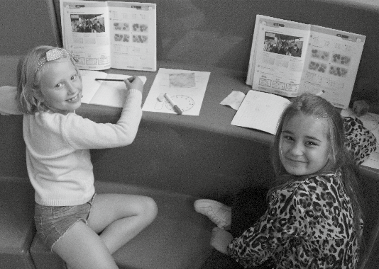 Twee vrolijke meisjes zijn aan het werk met hun schoolboeken in Het Stroomdal in Kampen. Twee vrolijke meisjes zijn aan het werk met hun schoolboeken in Het Stroomdal in Kampen.