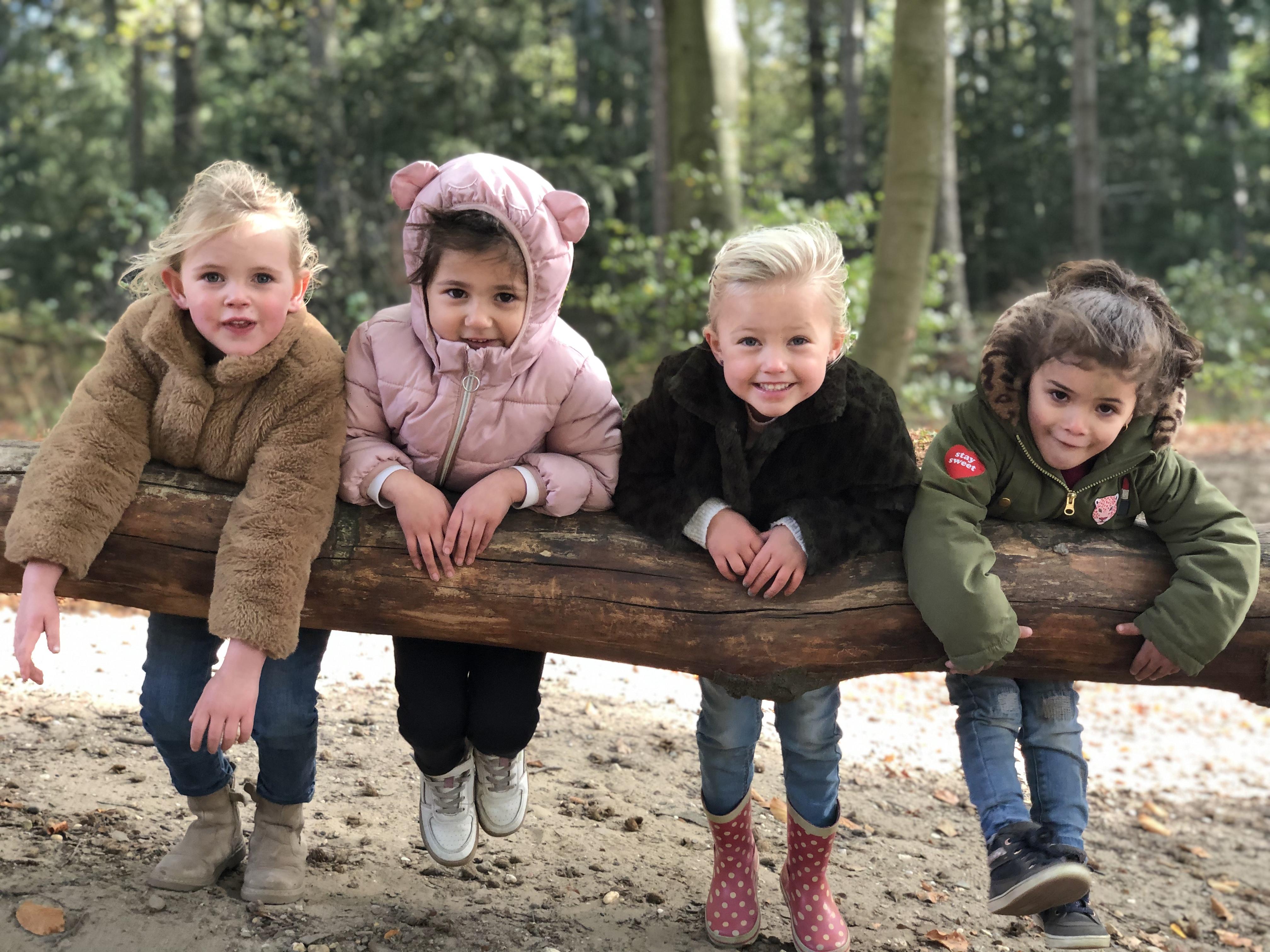 Vier blije kinderen spelen op een boomstronk op het schoolplein van IKC De Tragellijn in Lobith. Vier blije kinderen spelen op een boomstronk op het schoolplein van IKC De Tragellijn in Lobith.