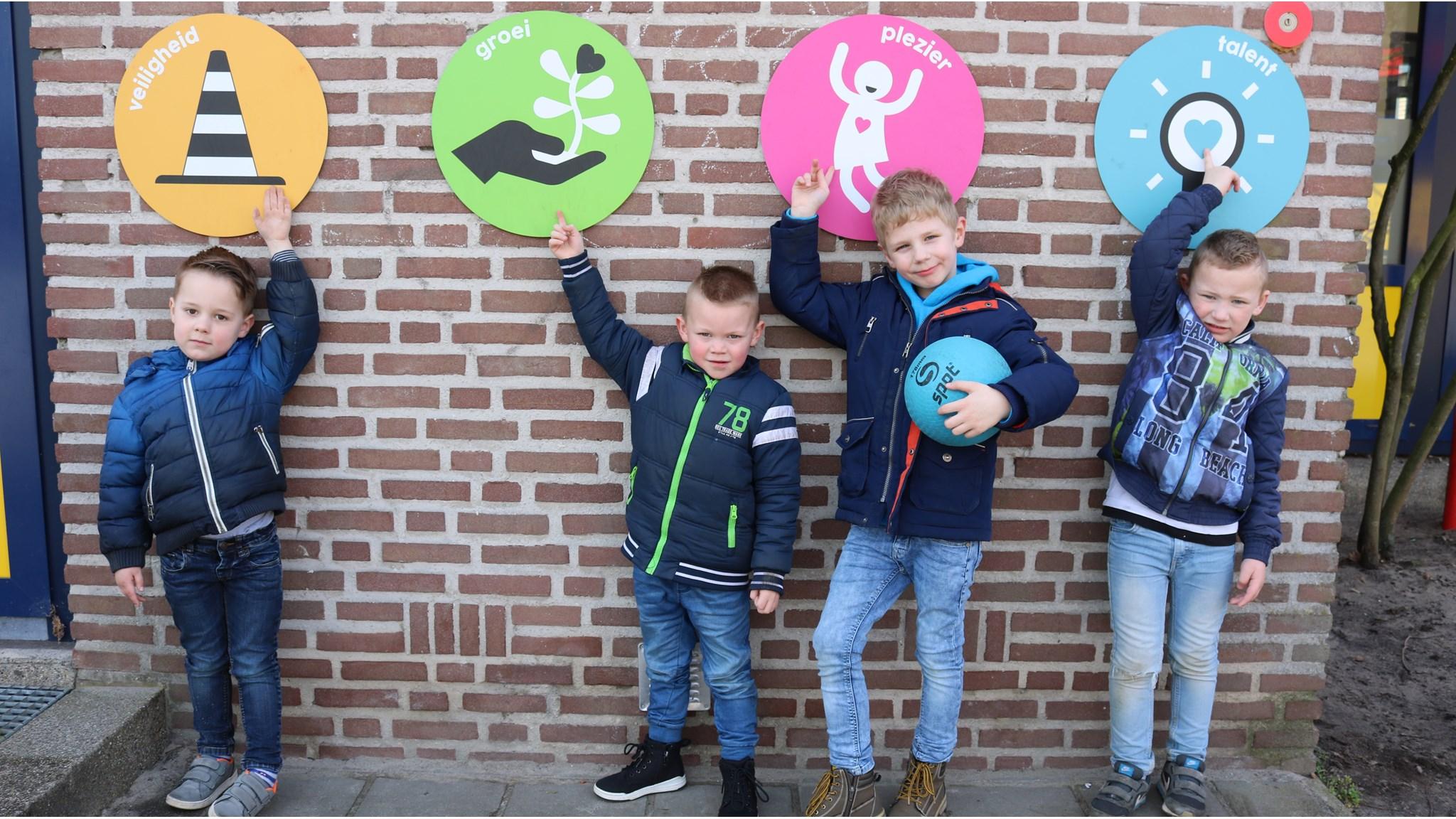 Vier kinderen tonen symbolen van veiligheid, groei, plezier en talent op Basisschool Widerode in Wierden.