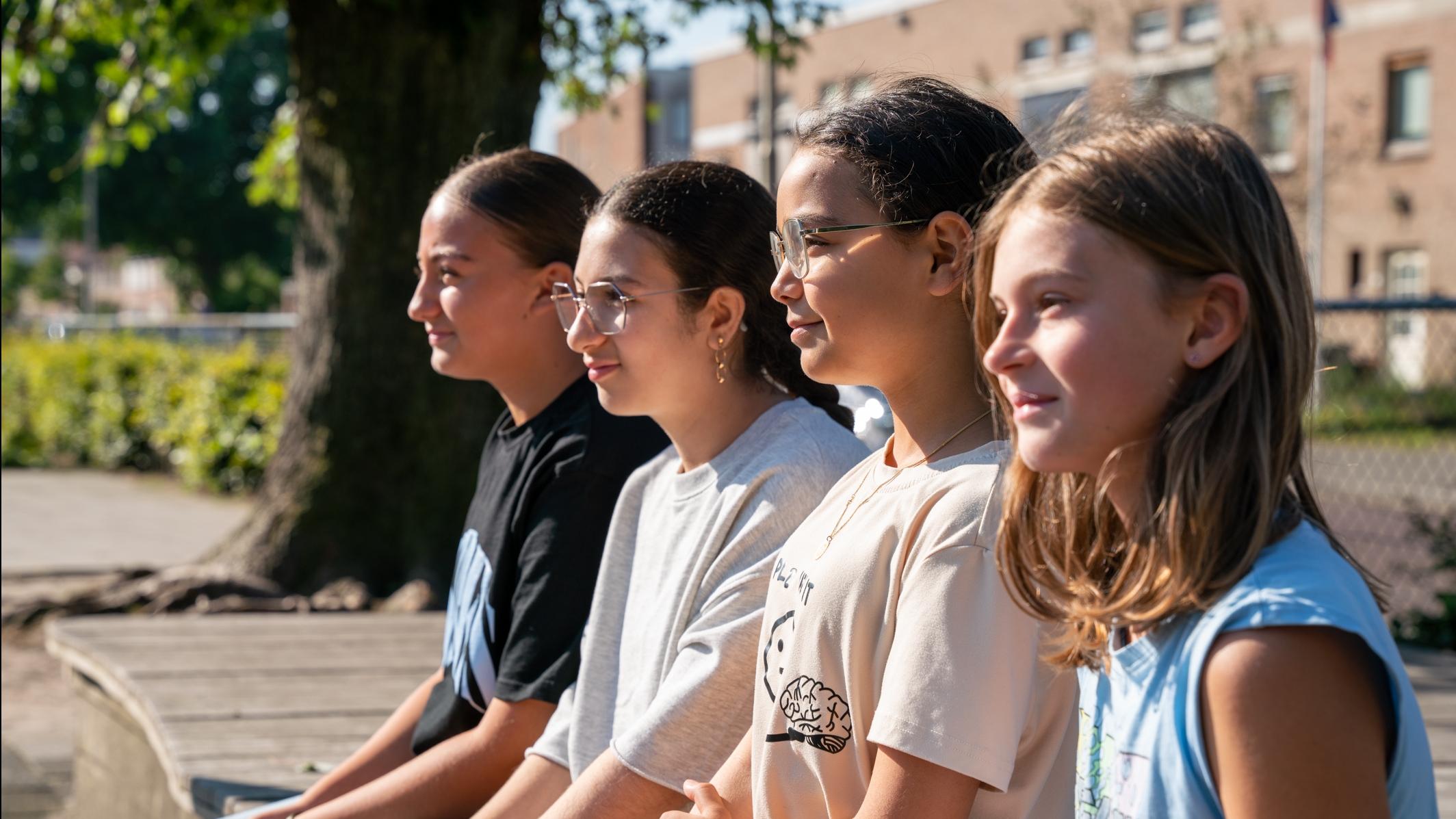 Vier leerlingen van BS Hertogin Johanna A in Oss zitten samen op het schoolplein. Vier leerlingen van BS Hertogin Johanna A in Oss zitten samen op het schoolplein.