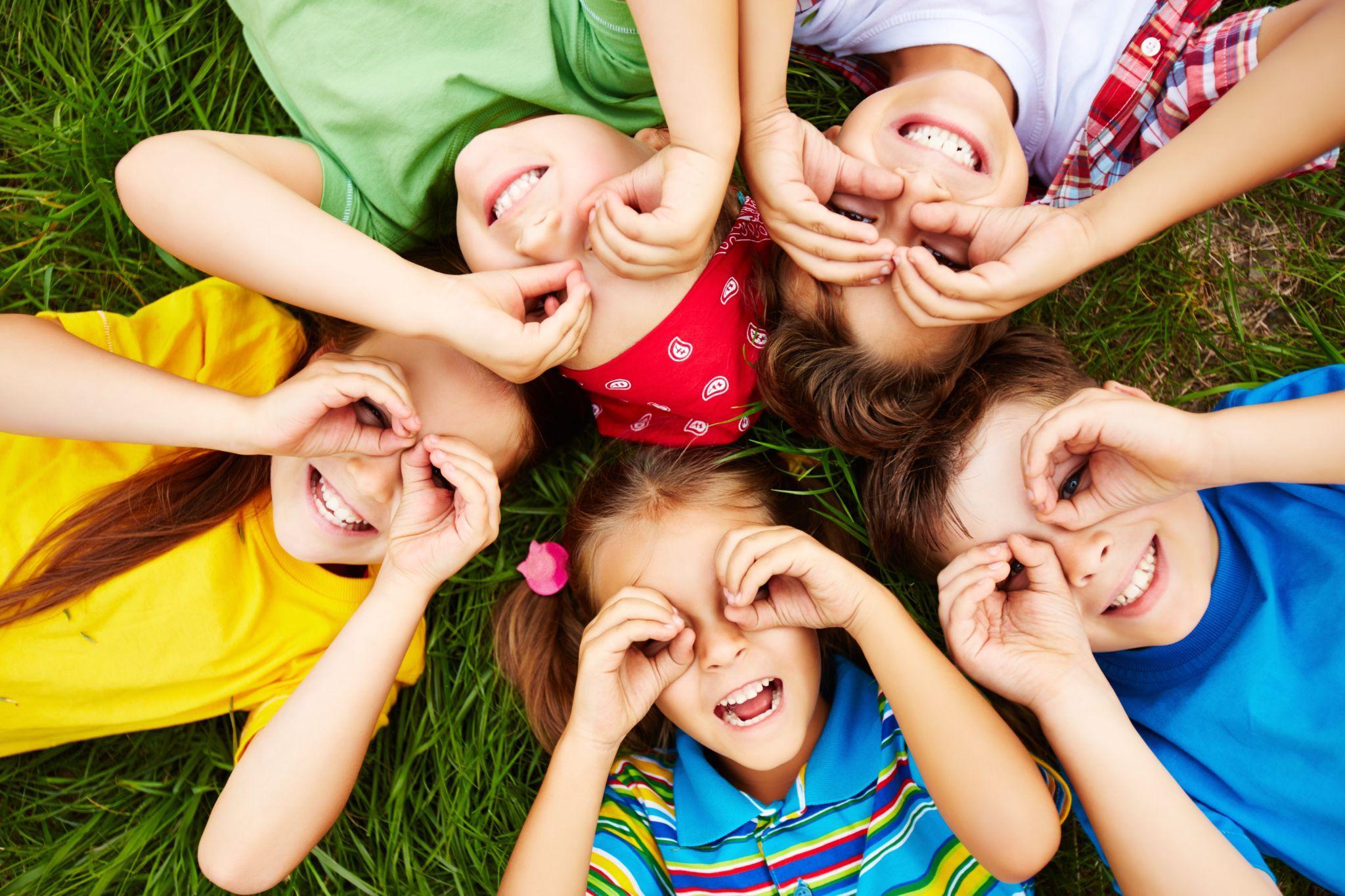 Vijf blije kinderen liggen op het gras van het schoolplein van WereldKidz Kameleon in Doorn. Vijf blije kinderen liggen op het gras van het schoolplein van WereldKidz Kameleon in Doorn.