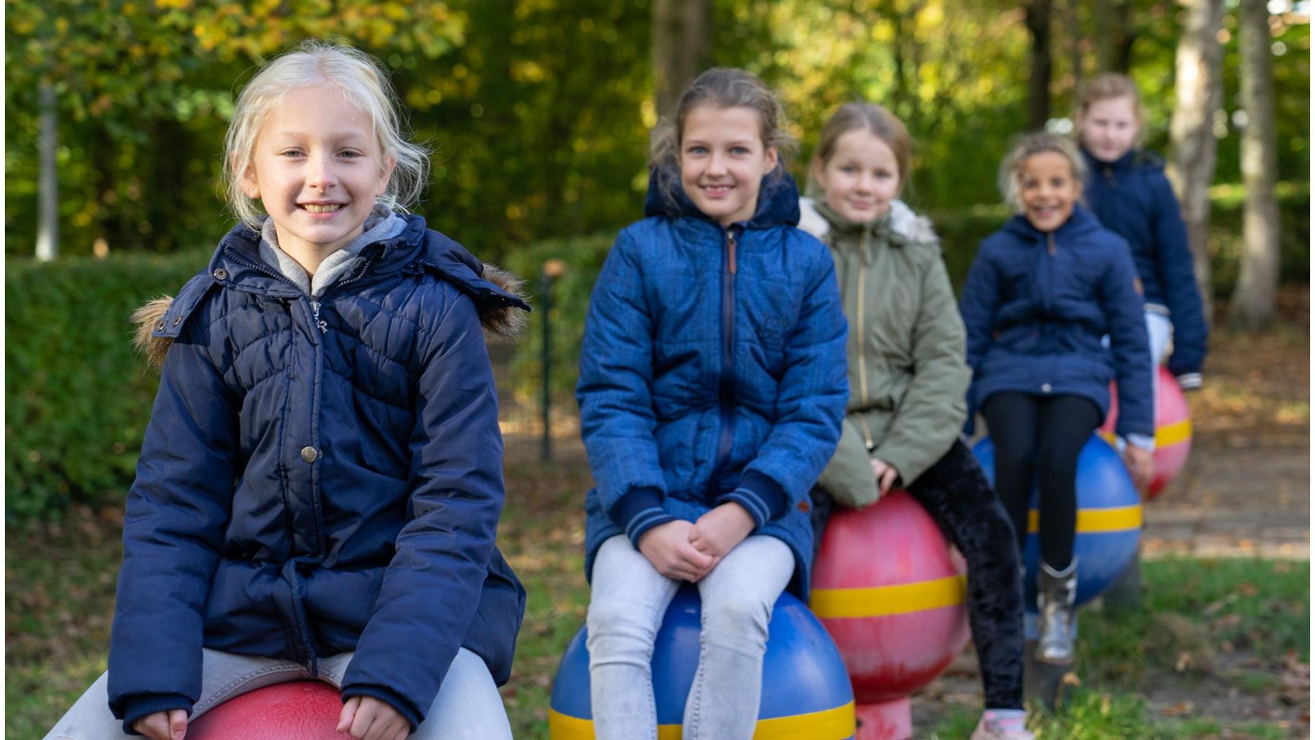 Vijf blije kinderen spelen op het schoolplein van De Zuidwester in Heiloo.
