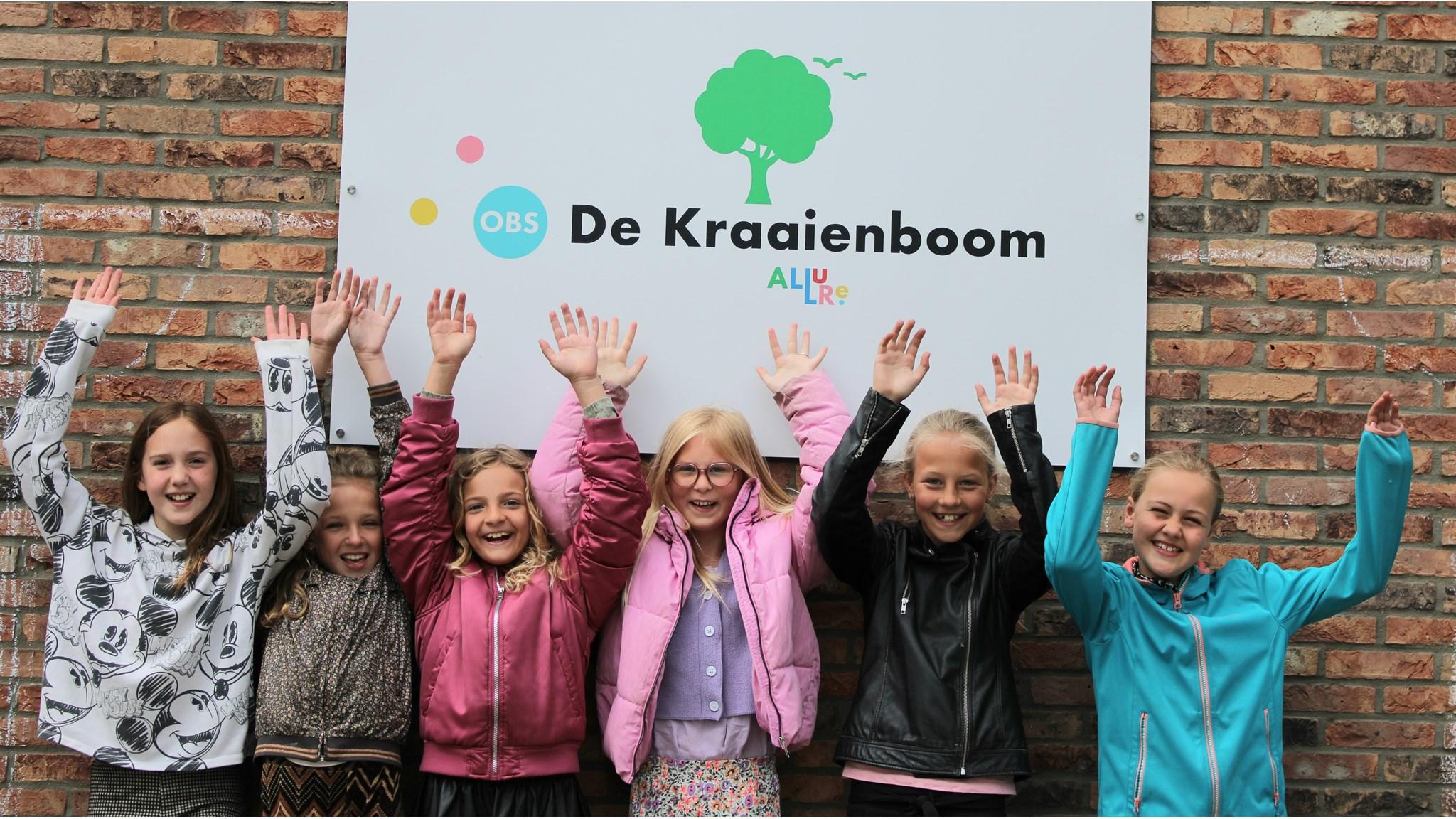 Vijf blije kinderen staan met uitgestoken handen voor de ingang van Openbare Basisschool de Kraaienboom in Benningbroek. Vijf blije kinderen staan met uitgestoken handen voor de ingang van Openbare Basisschool de Kraaienboom in Benningbroek.
