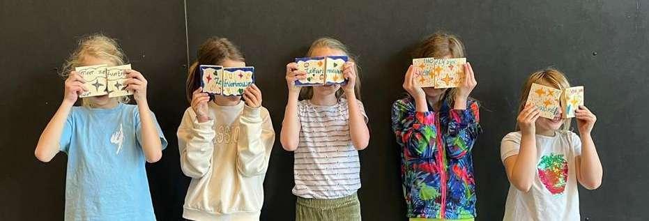 Vijf kinderen van Basisschool M Wiegman in Bergen (Noord-Holland) houden hun kunstwerkjes voor hun gezichten. Vijf kinderen van Basisschool M Wiegman in Bergen (Noord-Holland) houden hun kunstwerkjes voor hun gezichten.