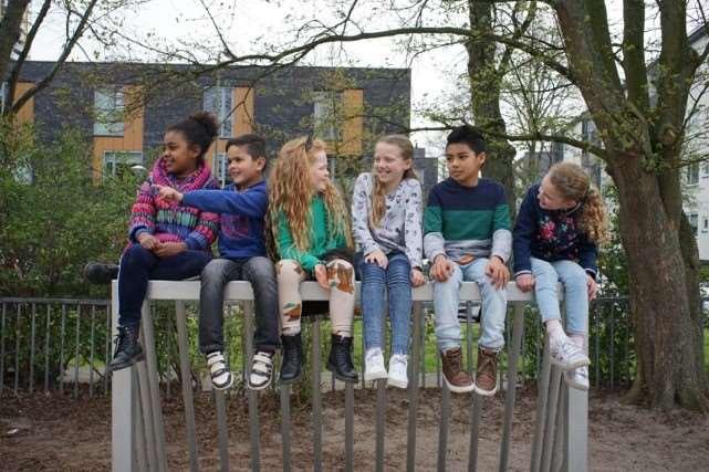 Zes blije kinderen spelen op het schoolplein van de Tamarschool in Den Haag. Zes blije kinderen spelen op het schoolplein van de Tamarschool in Den Haag.