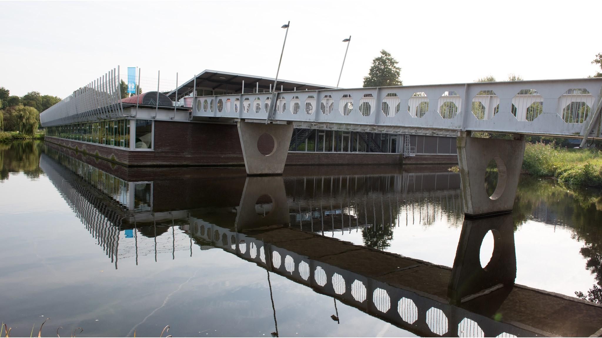 Zicht op het innovatieve gebouw van IKEC De Waterlelie in Leidschendam, weerspiegeld in het water. Zicht op het innovatieve gebouw van IKEC De Waterlelie in Leidschendam, weerspiegeld in het water.